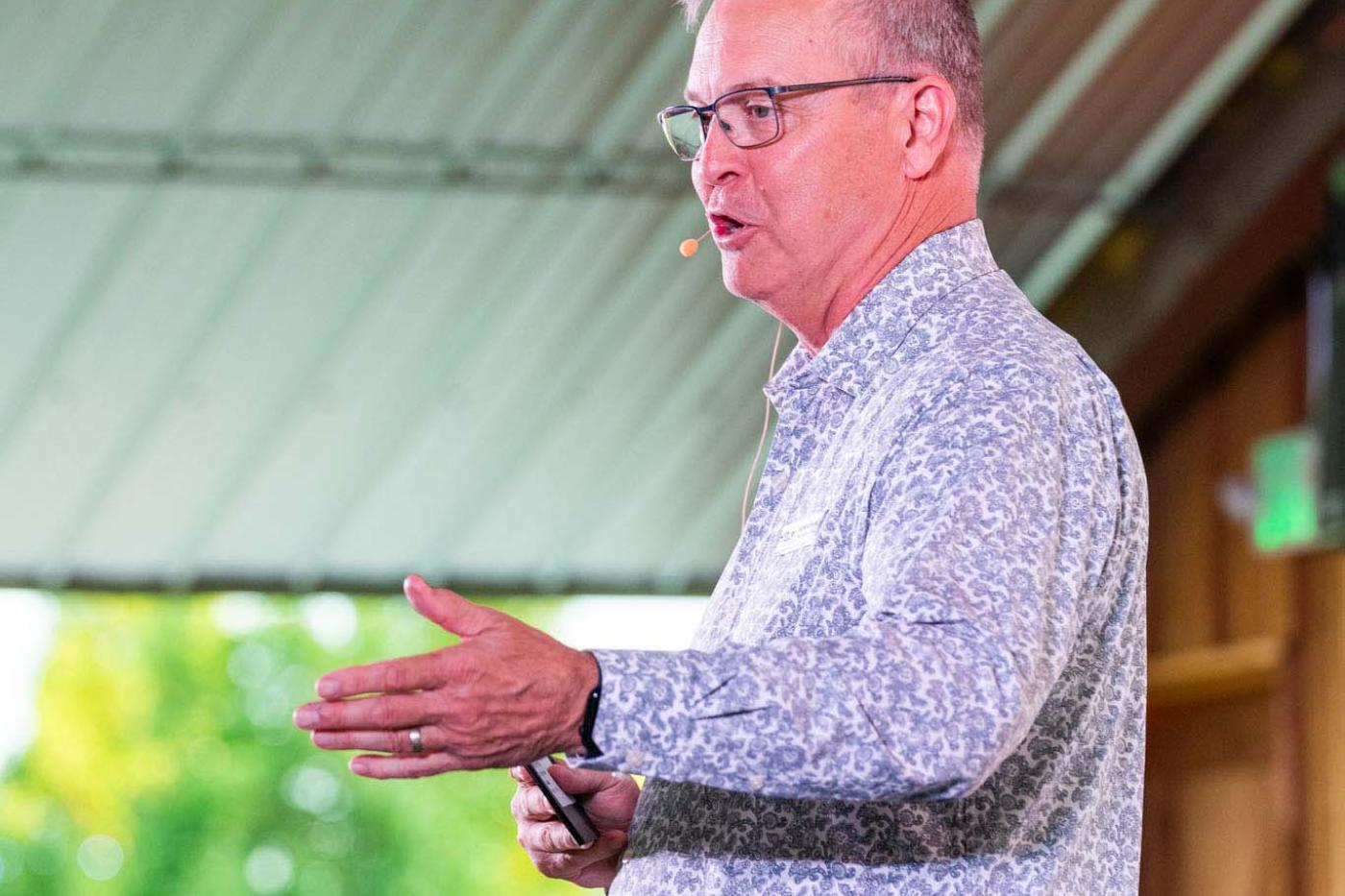 Side profile of a man in glasses giving a speech on stage